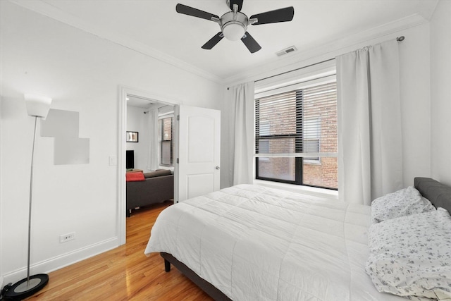 bedroom featuring ceiling fan, crown molding, and hardwood / wood-style floors