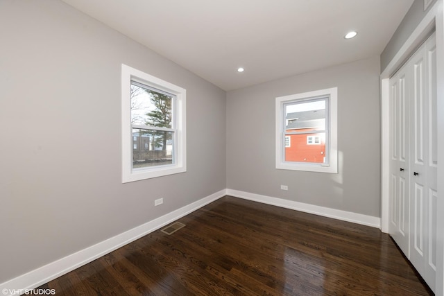 unfurnished bedroom with dark hardwood / wood-style flooring and a closet