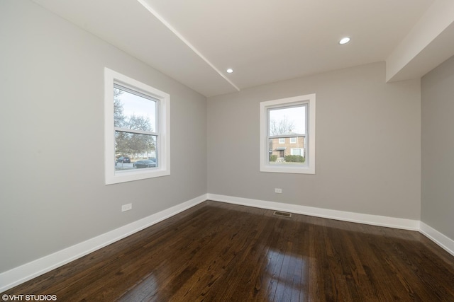 empty room featuring a healthy amount of sunlight and dark hardwood / wood-style floors