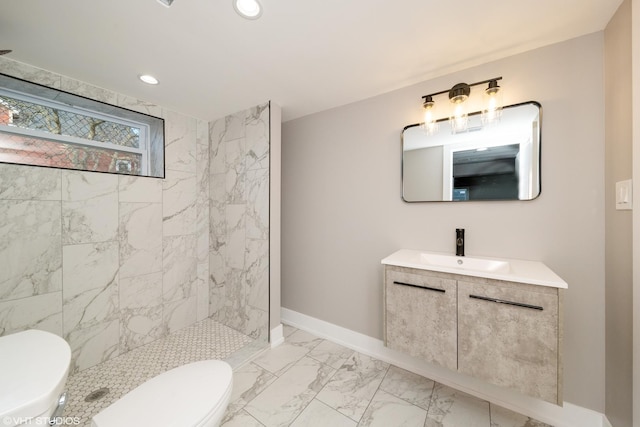 bathroom with tiled shower, vanity, and toilet