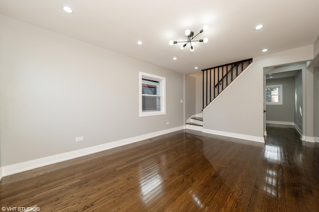 unfurnished living room featuring a notable chandelier and dark hardwood / wood-style flooring