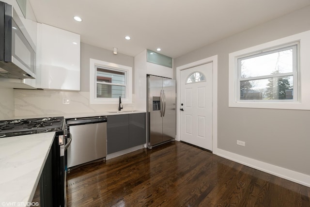 kitchen featuring sink, stainless steel appliances, light stone counters, tasteful backsplash, and white cabinets