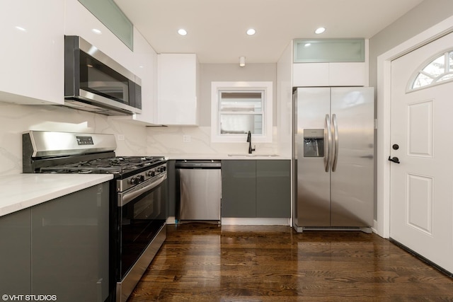 kitchen with appliances with stainless steel finishes, dark hardwood / wood-style floors, sink, and white cabinets