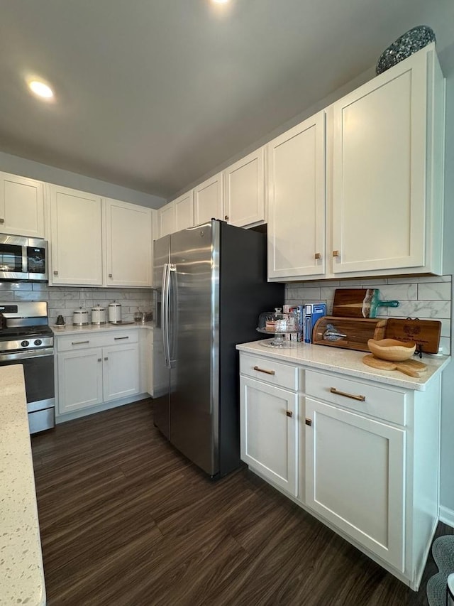 kitchen with dark hardwood / wood-style flooring, tasteful backsplash, white cabinets, and appliances with stainless steel finishes