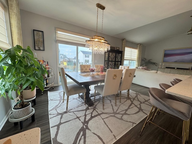 dining space with a notable chandelier, hardwood / wood-style flooring, and vaulted ceiling