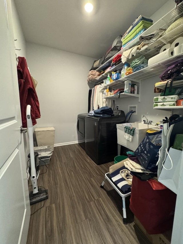 clothes washing area featuring dark hardwood / wood-style floors, sink, and washing machine and clothes dryer