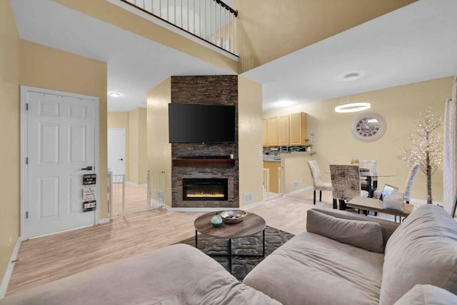 living room with light hardwood / wood-style floors, a high ceiling, and a fireplace