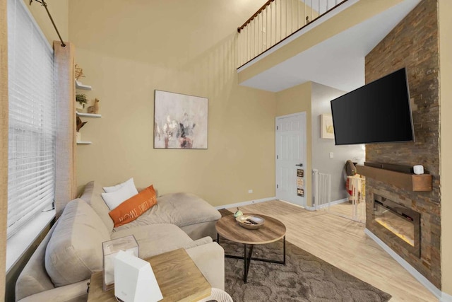 living room with a wealth of natural light, a stone fireplace, and hardwood / wood-style flooring