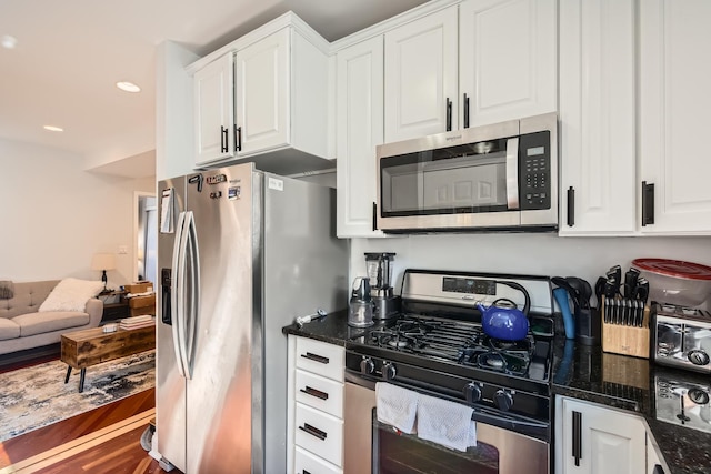 kitchen with dark stone counters, stainless steel appliances, and white cabinetry