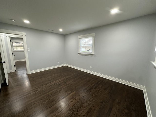 spare room featuring dark hardwood / wood-style flooring and a healthy amount of sunlight