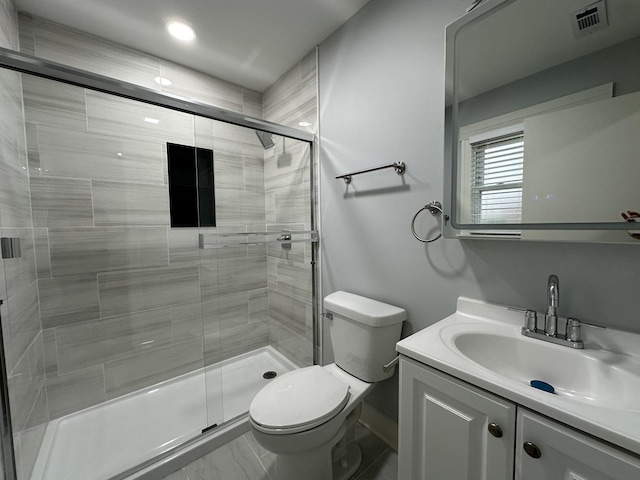 bathroom with toilet, vanity, and a shower with shower door