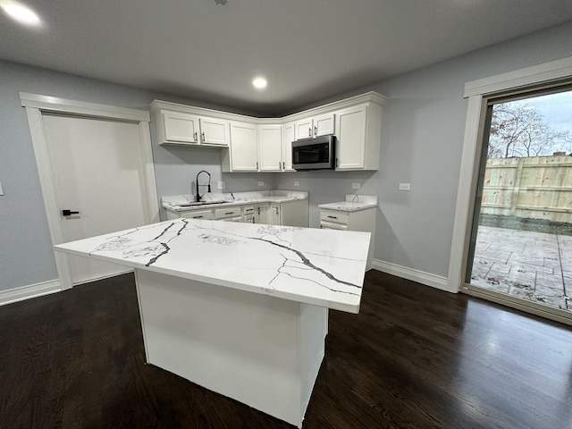 kitchen featuring dark wood-style floors, stainless steel microwave, white cabinetry, and a sink