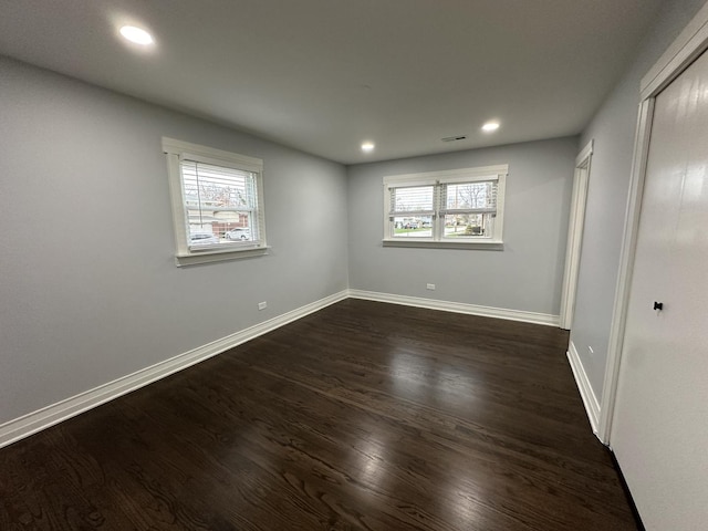 unfurnished bedroom featuring multiple windows, baseboards, and dark wood-style flooring