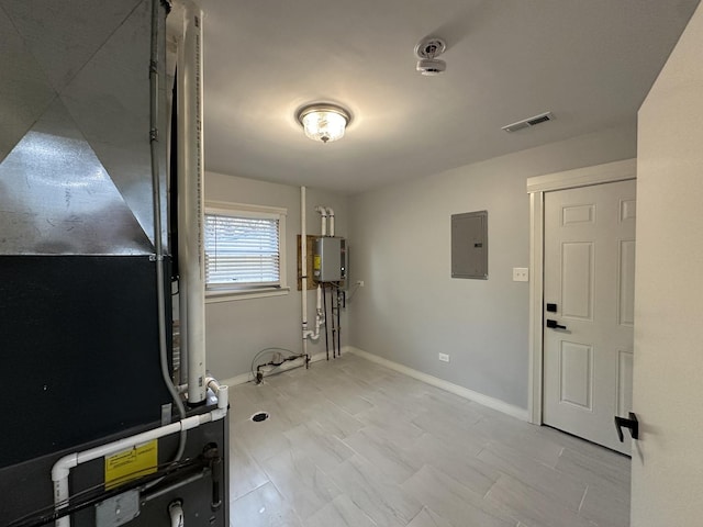 interior space with heating unit, baseboards, visible vents, electric panel, and water heater