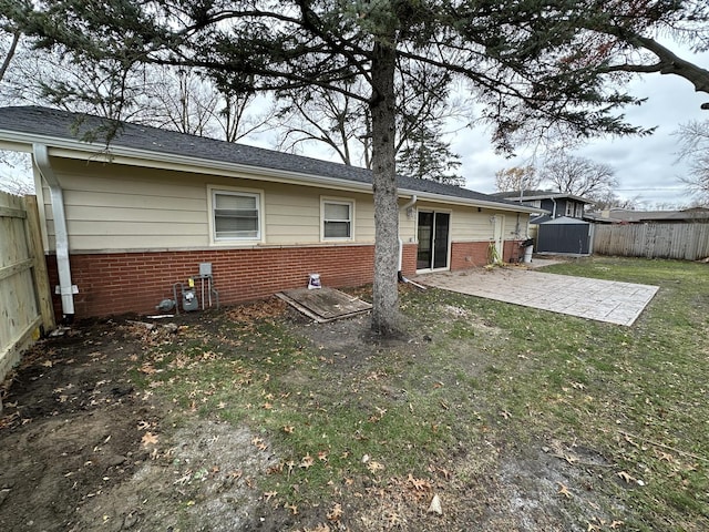 back of house featuring brick siding, a shed, an outdoor structure, a fenced backyard, and a patio area