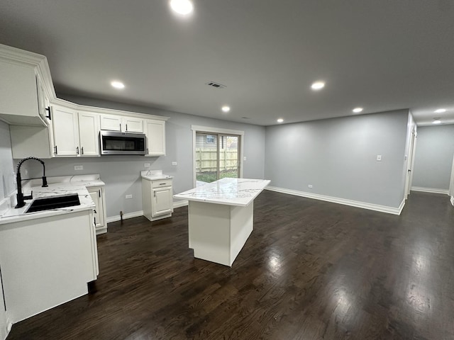 kitchen with white cabinets, dark wood-type flooring, a center island, and sink