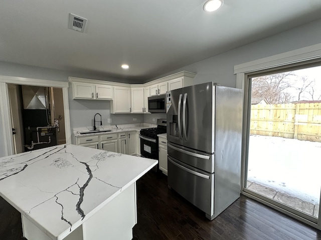 kitchen with visible vents, a sink, appliances with stainless steel finishes, white cabinets, and dark wood-style flooring