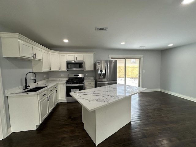 kitchen featuring visible vents, a sink, dark wood-style floors, a center island, and stainless steel appliances