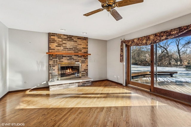 unfurnished living room featuring hardwood / wood-style flooring, ceiling fan, and a fireplace