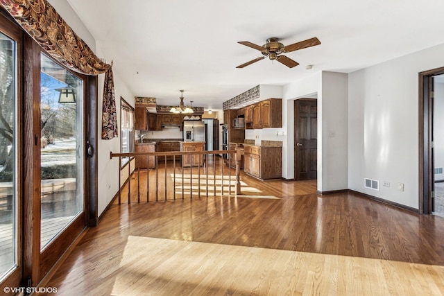 kitchen with sink, kitchen peninsula, ceiling fan with notable chandelier, light hardwood / wood-style flooring, and extractor fan