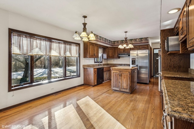 kitchen featuring dishwasher, a notable chandelier, a kitchen island, stainless steel refrigerator with ice dispenser, and decorative light fixtures