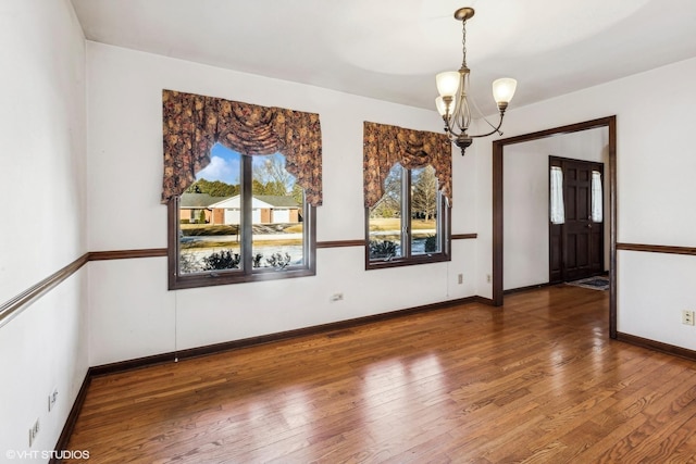 spare room featuring a notable chandelier, dark hardwood / wood-style flooring, and plenty of natural light