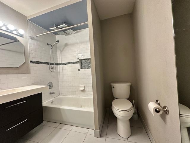 full bathroom featuring tile patterned flooring, tiled shower / bath combo, vanity, and toilet