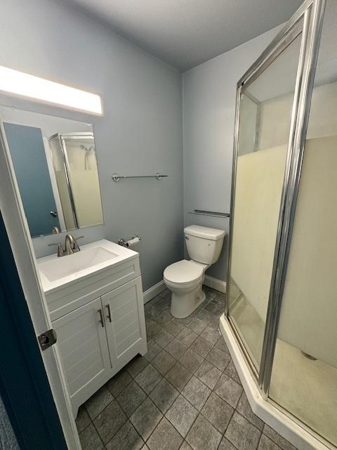 bathroom with a shower with door, vanity, and toilet