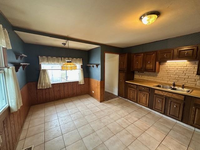 kitchen featuring wood walls, hanging light fixtures, and sink