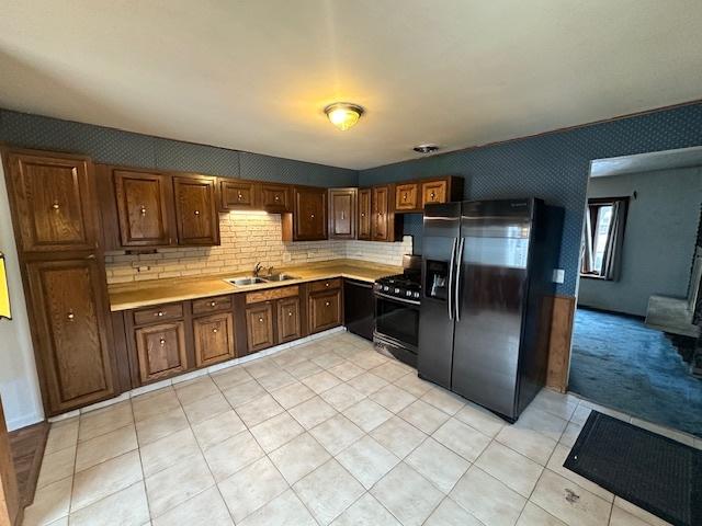 kitchen with black appliances, decorative backsplash, and sink