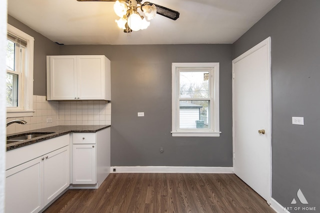 kitchen with white cabinets, dark stone countertops, dark hardwood / wood-style floors, decorative backsplash, and sink