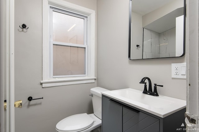 bathroom with toilet, vanity, and plenty of natural light