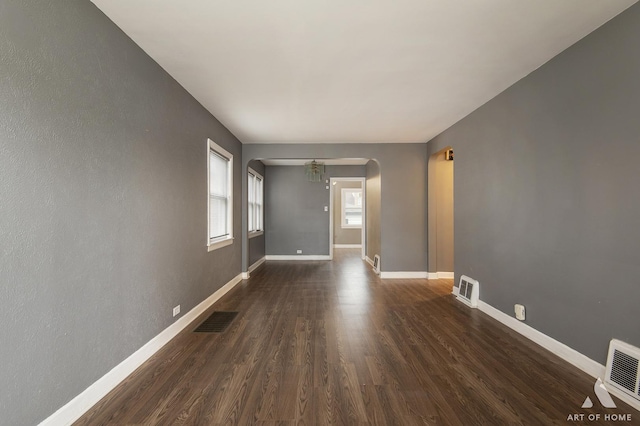 spare room with an inviting chandelier and dark wood-type flooring