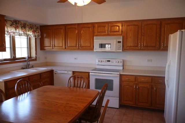 kitchen featuring light countertops, white appliances, brown cabinets, and a sink