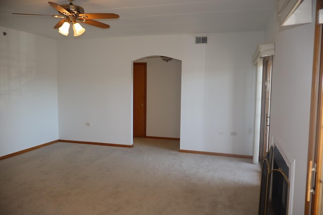 unfurnished room featuring light carpet, baseboards, visible vents, and arched walkways