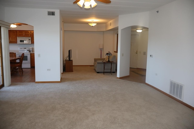 unfurnished room with light carpet, visible vents, arched walkways, and ceiling fan