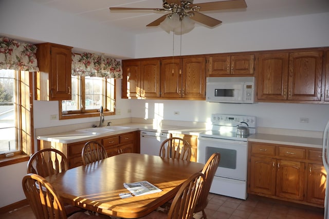 kitchen with brown cabinets, white appliances, light countertops, and a sink