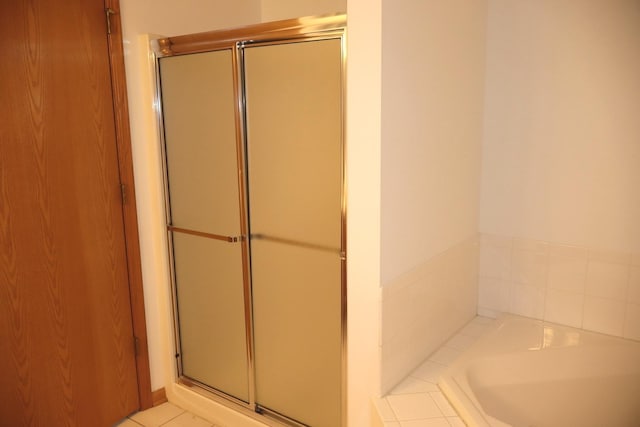 full bathroom featuring a stall shower, tile patterned flooring, and a bath