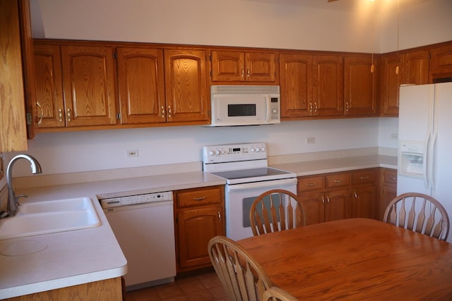 kitchen featuring brown cabinetry, white appliances, light countertops, and a sink