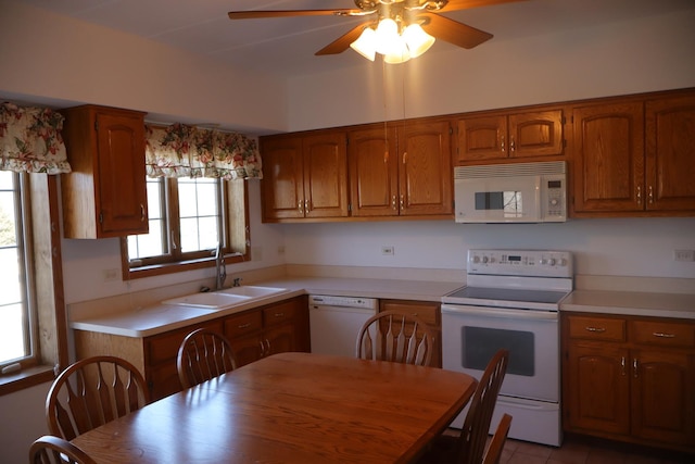 kitchen with white appliances, brown cabinetry, a sink, and light countertops