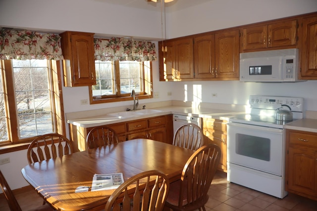 kitchen with white appliances, light countertops, a sink, and brown cabinetry