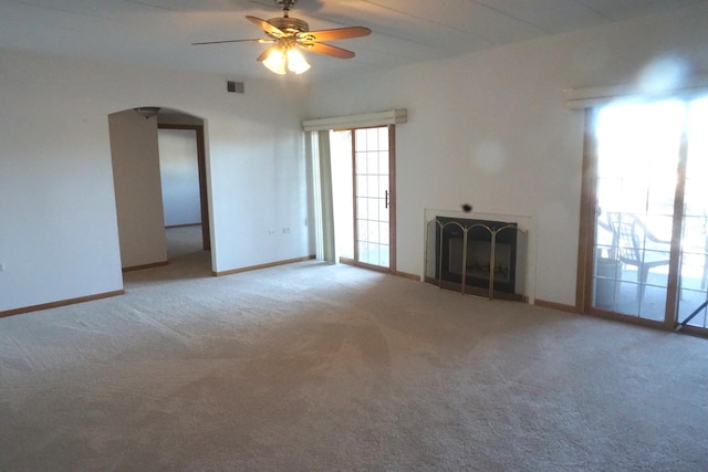 unfurnished living room featuring arched walkways, carpet, a fireplace, visible vents, and baseboards