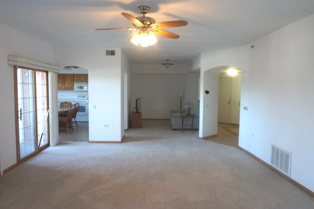 empty room with light colored carpet, arched walkways, and visible vents