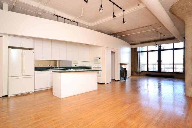 kitchen with white appliances, white cabinets, a kitchen island, and a high ceiling