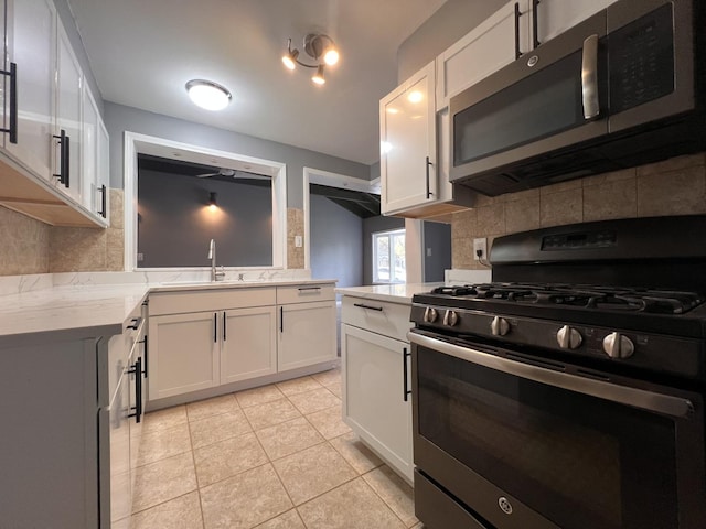 kitchen with light tile patterned flooring, sink, stainless steel appliances, and white cabinetry