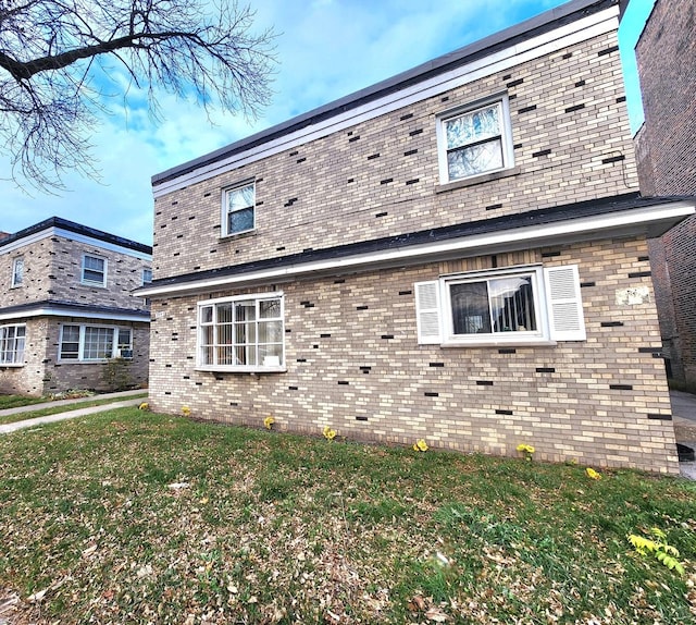 view of property exterior featuring brick siding and a lawn