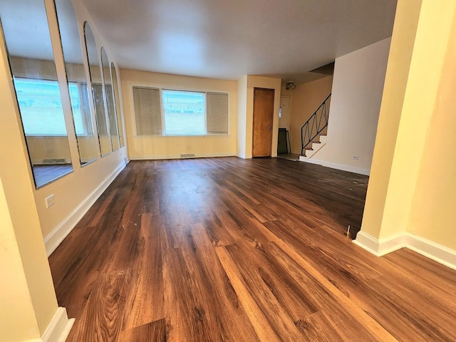 unfurnished living room featuring visible vents, stairway, wood finished floors, and baseboards