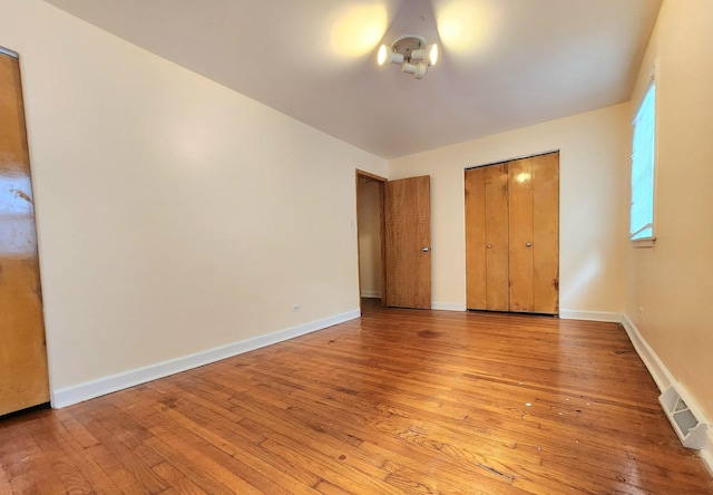 unfurnished bedroom with light wood finished floors, visible vents, and baseboards