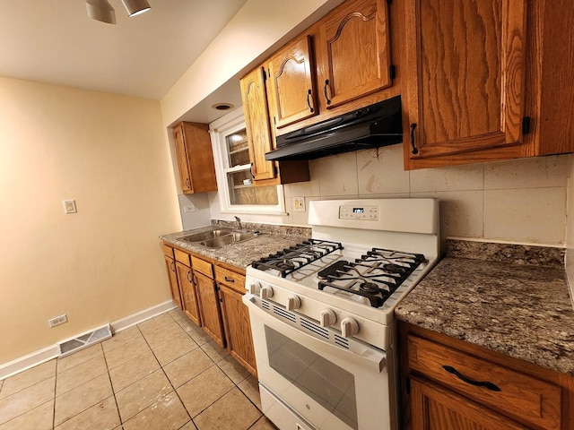 kitchen with visible vents, gas range gas stove, under cabinet range hood, brown cabinetry, and a sink