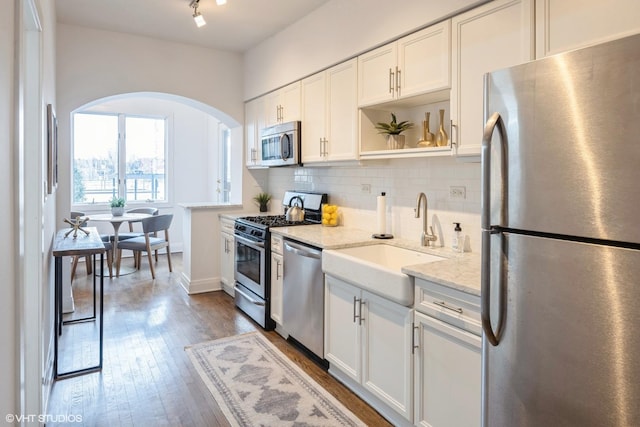 kitchen featuring light stone countertops, appliances with stainless steel finishes, white cabinetry, and sink